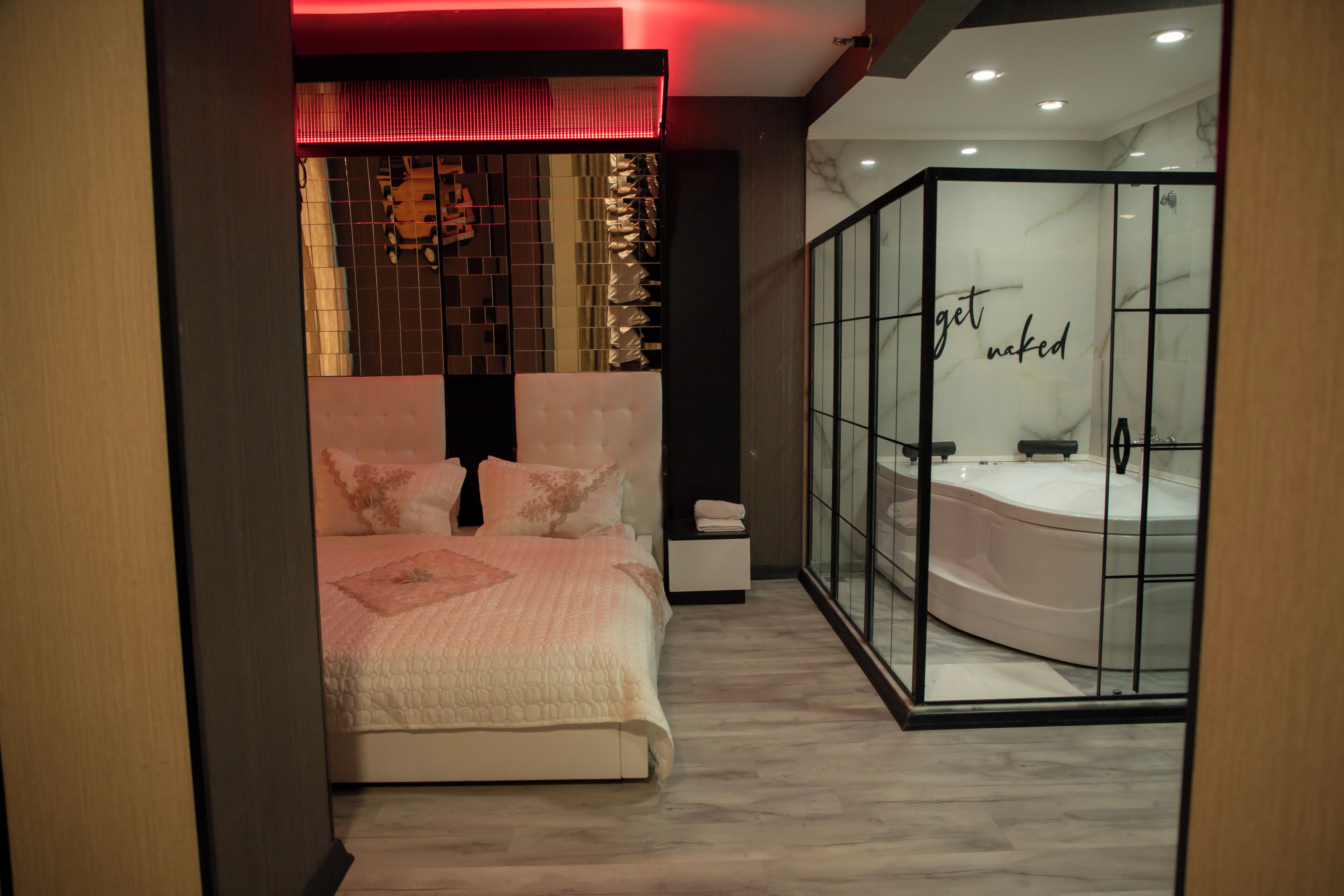 A bedroom with a large bed, a nightstand, and a glass-enclosed bathroom with a bathtub.