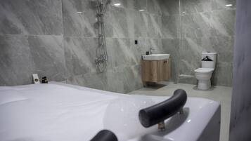 Ein modernes Badezimmer mit einer großen Badewanne, einer Dusche und einem WC.
