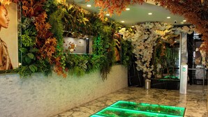 En lobby med et akvarium oplyst med grønt lys, frodige indendørsplanter og en marmorgulv.