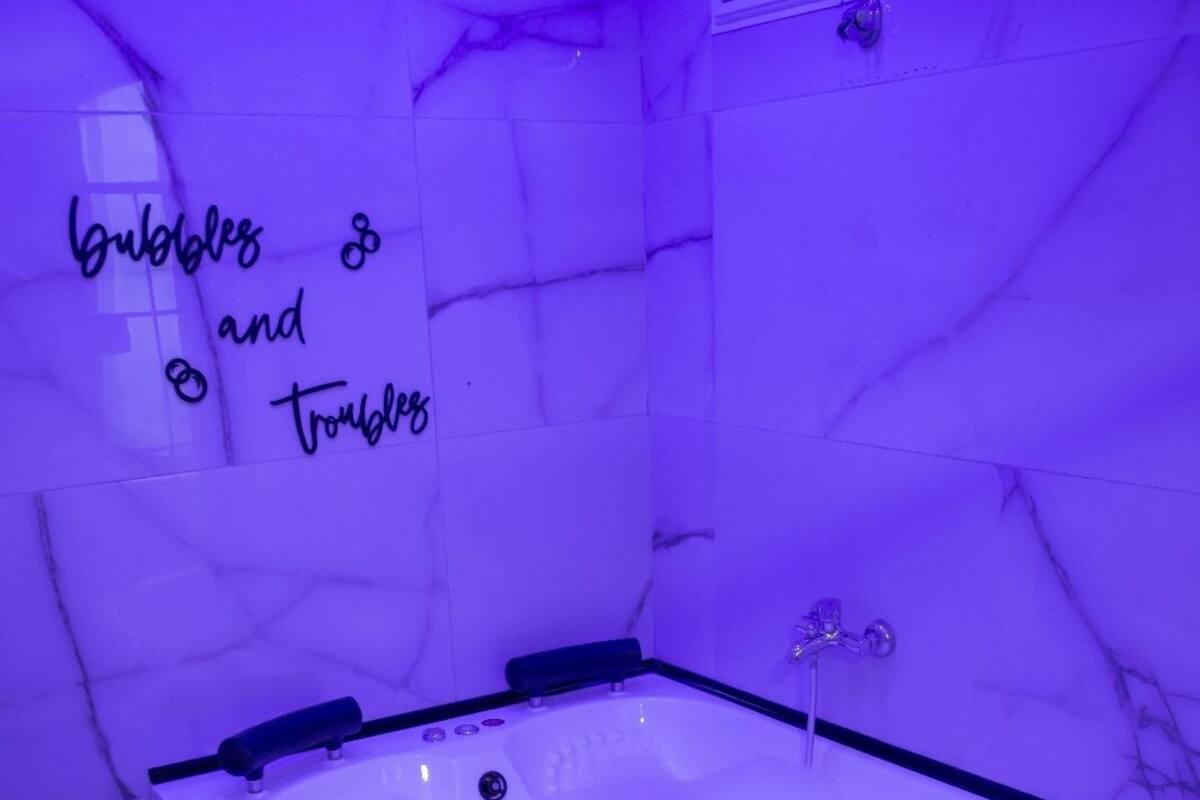 A bathroom with a large bathtub, marble walls, and a sign that reads 'bubbles and troubles'.