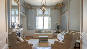 Ein geräumiges Wohnzimmer mit großem Fenster, aufwendiger Deckenverzierungen und klassischen Möbeln.