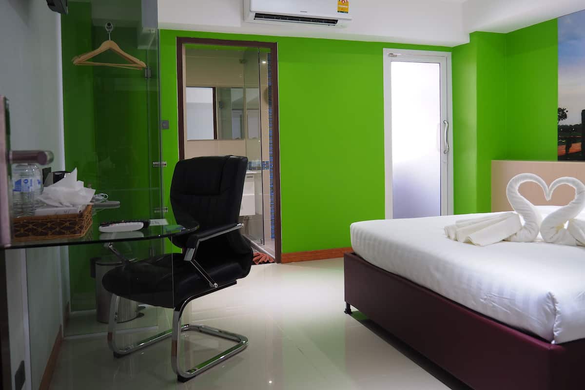 A hotel room with a bed, a chair, a desk, and a mirror.