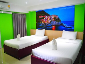 A hotel room with two beds, green walls, a large window, and an air conditioning unit. - Blue Orchids Hotel (Hat Yai)