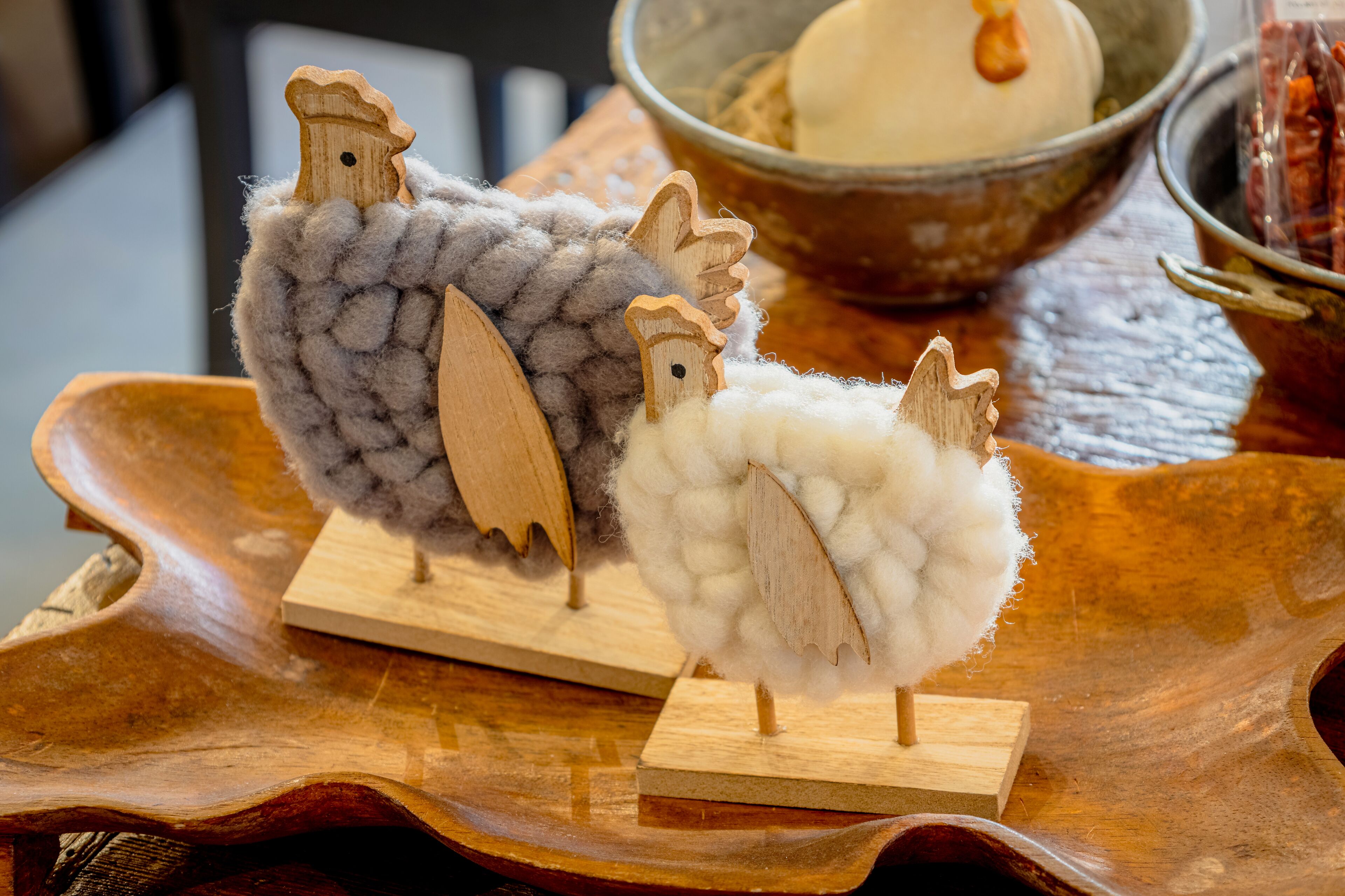 Zwei hölzerne Schafskulpturen auf einer Holzschale.