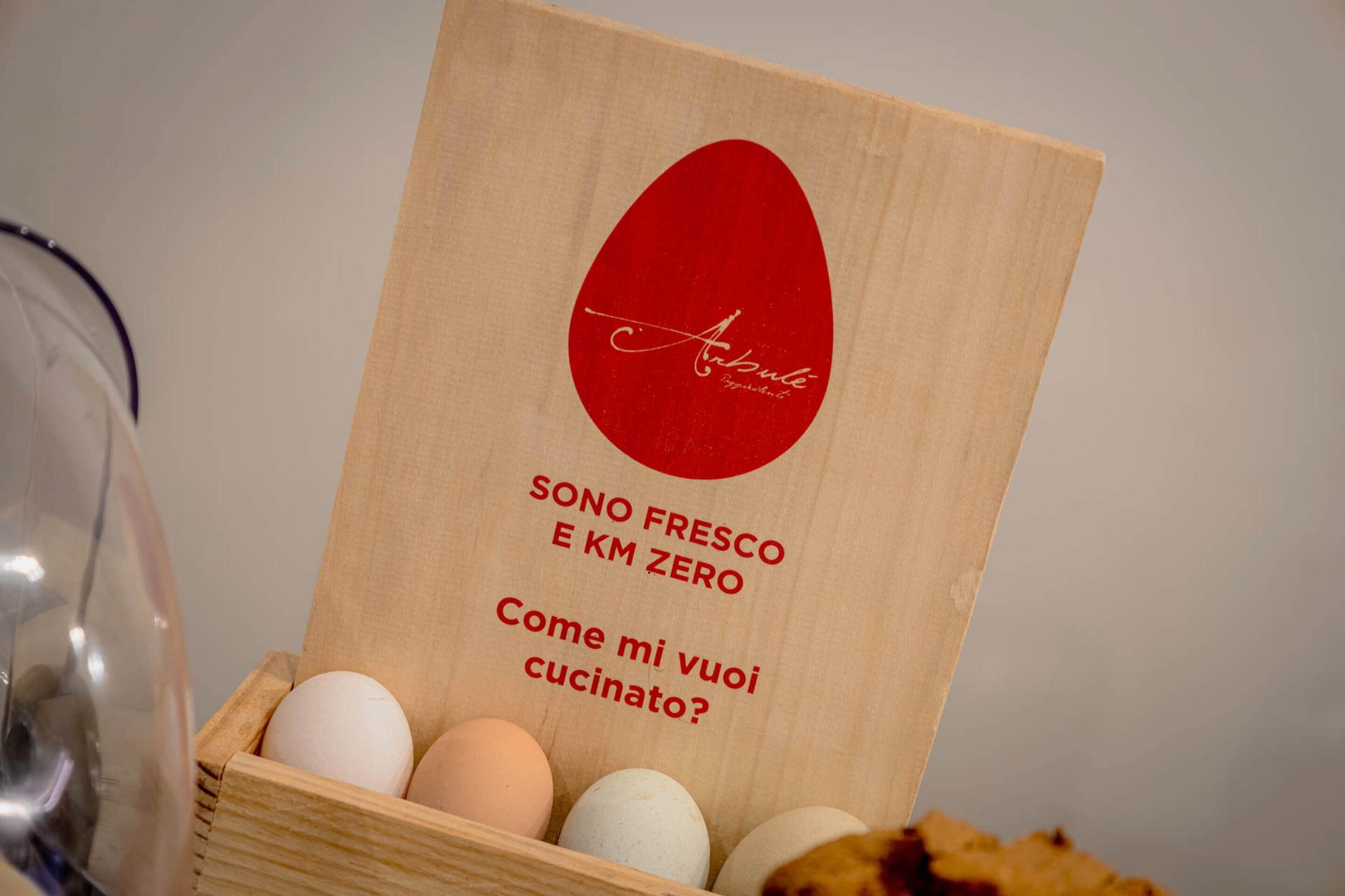 Una caja de madera con etiqueta roja y huevos adentro.