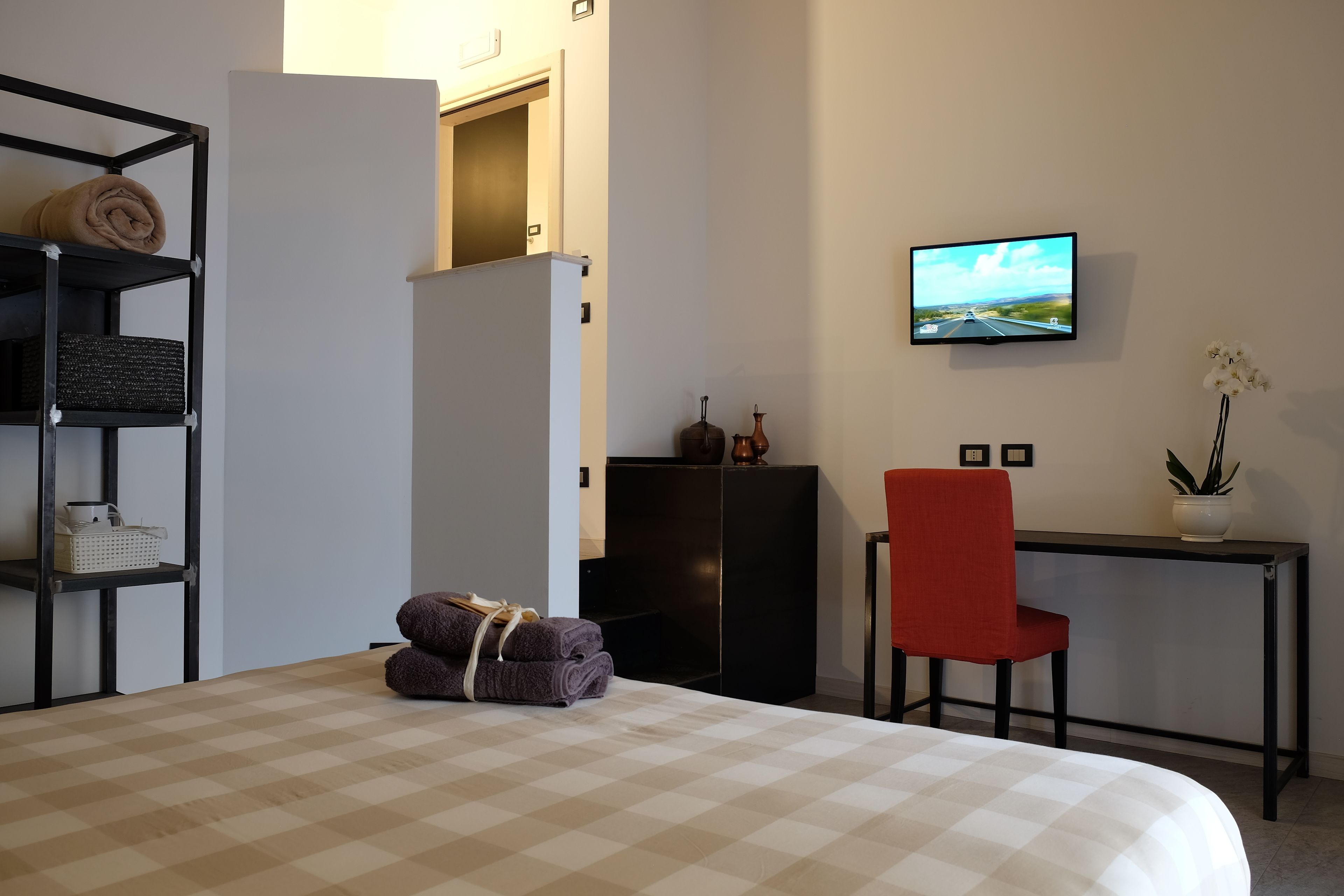 A hotel room with a bed, a desk, a TV, and a chair.
