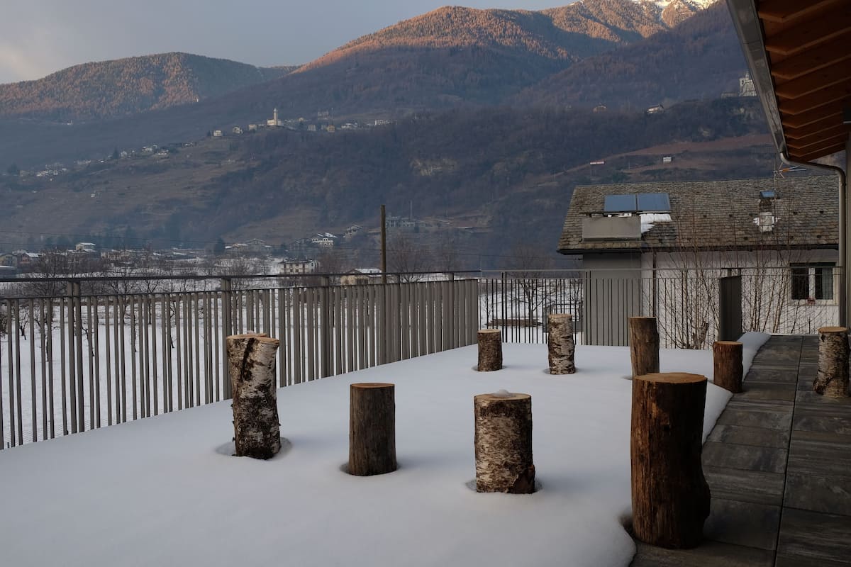 A snowy outdoor area with wooden stumps and a metal fence.