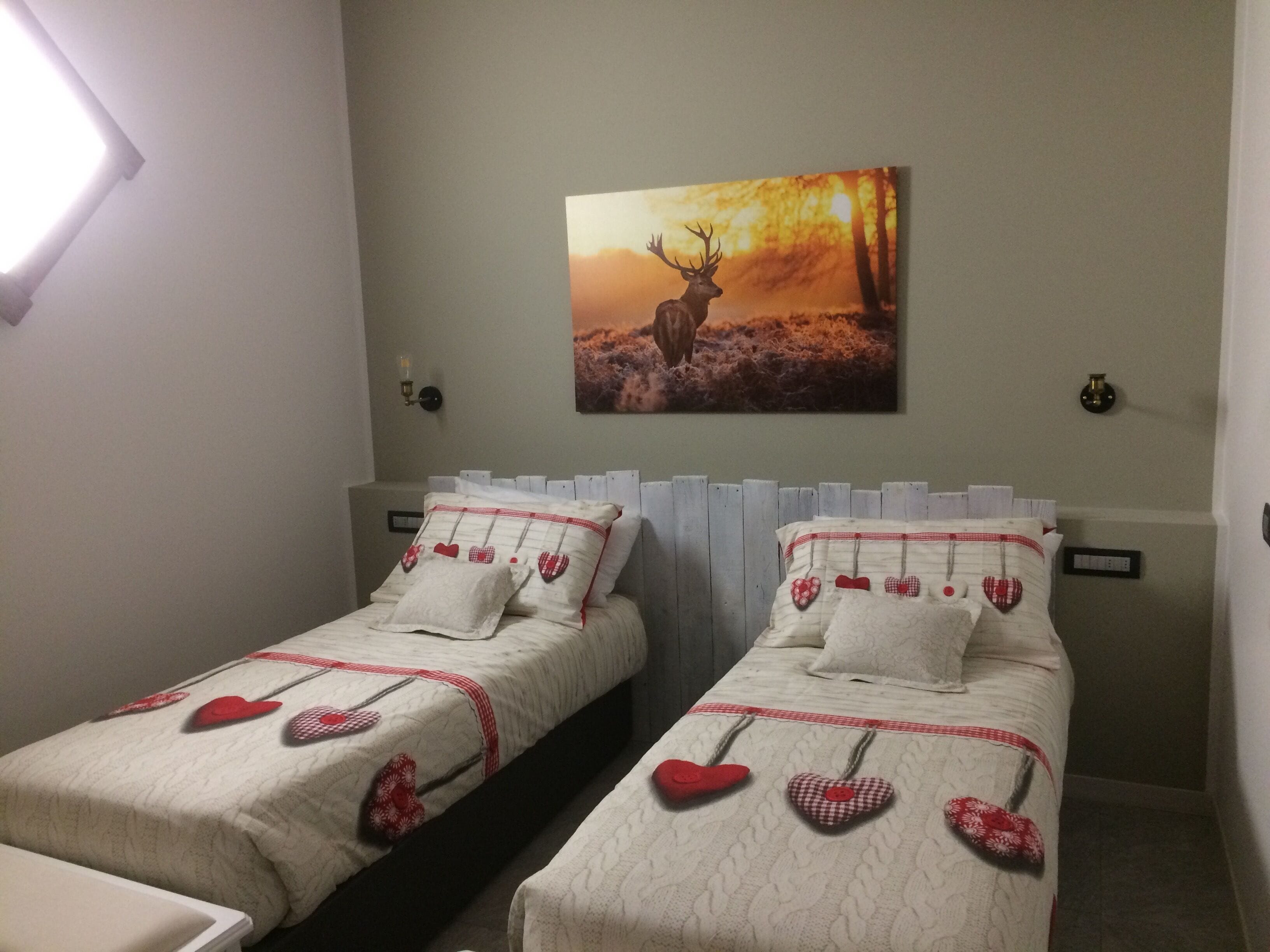 Un dormitorio con dos camas, cada una con almohadas con forma de corazón y una colcha acolchada.