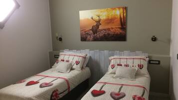 Un dormitorio con dos camas, cada una con almohadas con forma de corazón y una colcha acolchada.