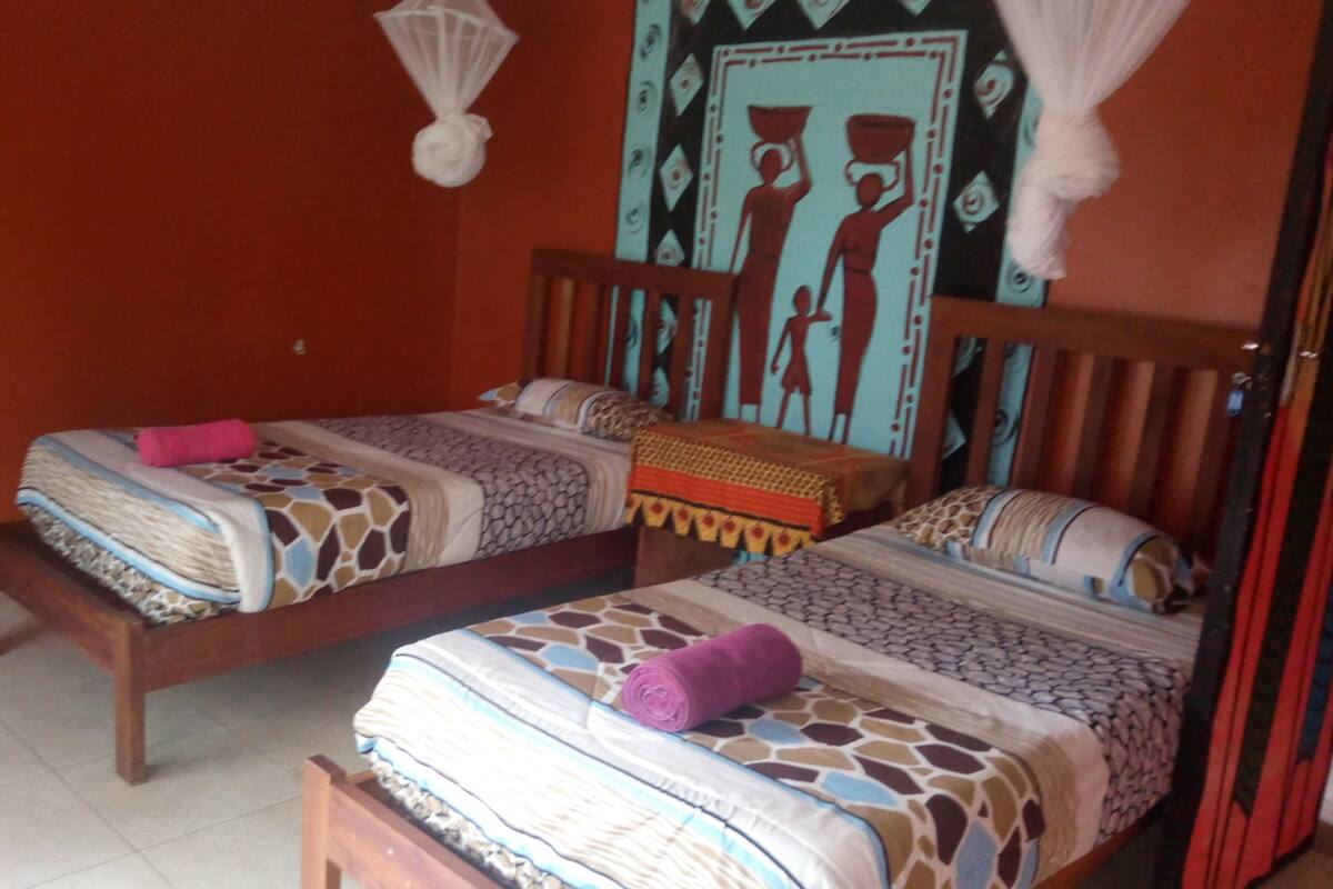 A room with two wooden beds, each with patterned bedding and pillows.