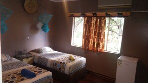 Una habitación con dos camas, una mesita y una ventana con cortinas.