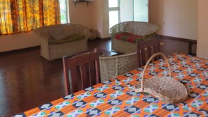 Una habitación con dos sillones de mimbre, una mesa con mantel estampado y una ventana con cortinas.