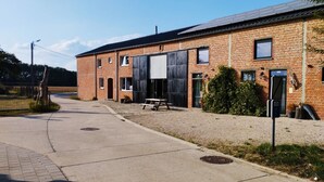 A brick building with large windows and a covered outdoor area. - De Smishoeve (Heers)