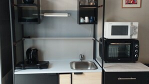 A compact kitchenette with a microwave, kettle, and a sink. - De Smishoeve (Heers)