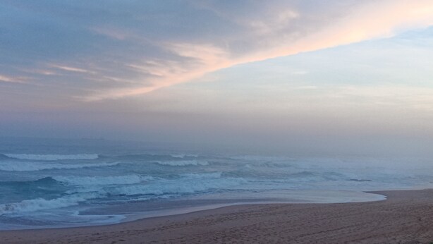 Uma praia com ondas e céu nublado.