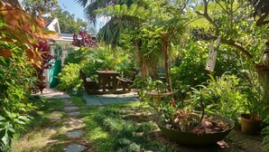 Um jardim com caminho de pedra, móveis de madeira e diversas plantas.