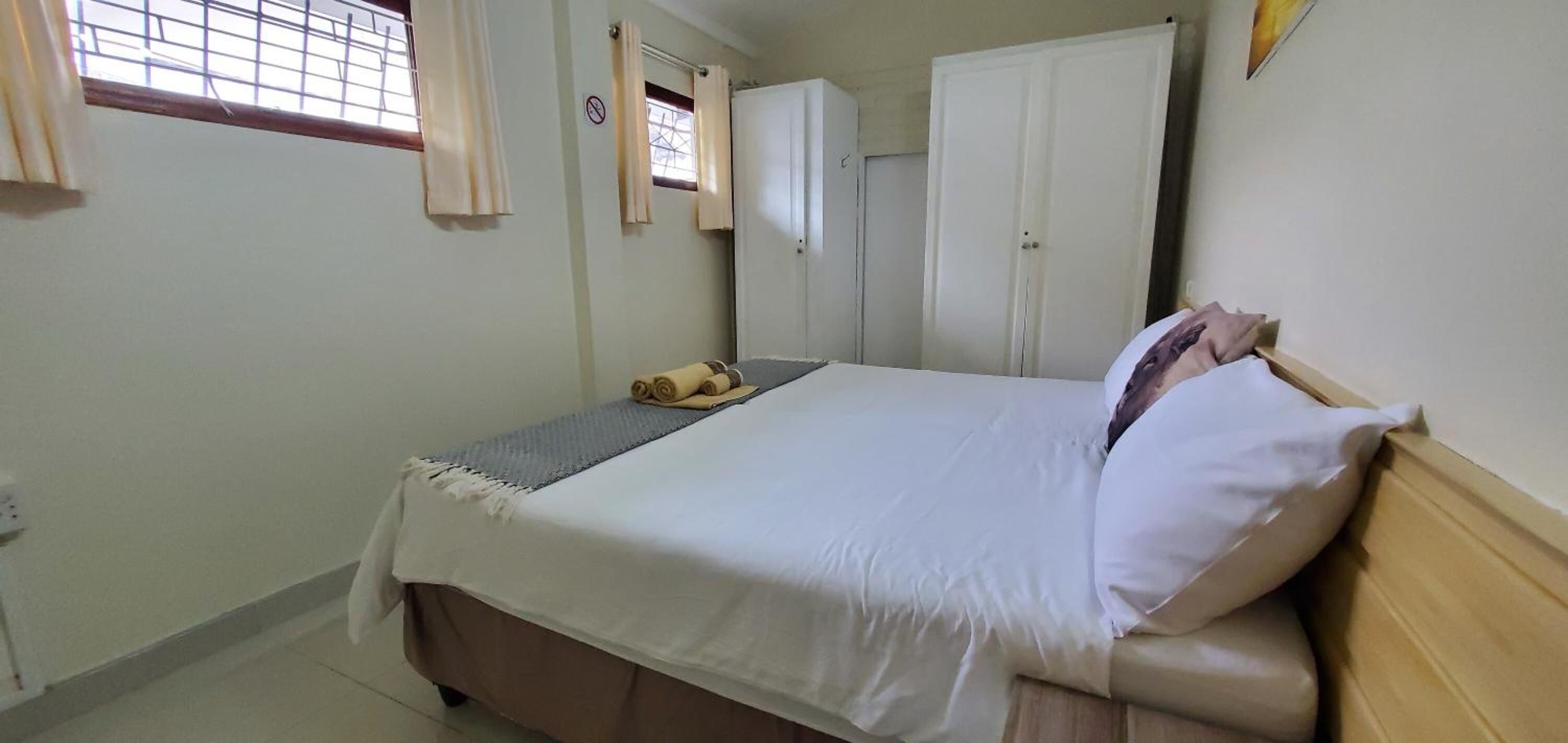 Un dormitorio con cama, armario y ventana con cortinas.