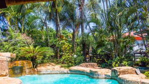 Uma piscina rodeada por vegetação tropical e formações rochosas.