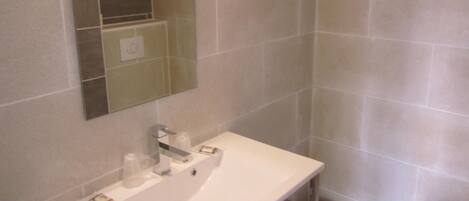 A bathroom with a white sink, mirror, and tiled walls.