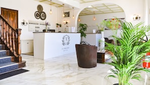 Un vestíbulo de hotel con una recepción, una escalera y una planta grande en maceta.