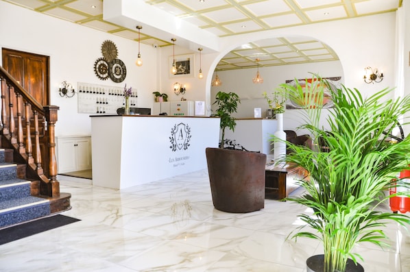 Un vestíbulo de hotel con una recepción, una escalera y una planta grande en maceta.