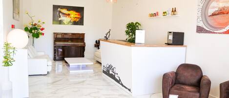 A modern living room with a piano, a reception desk, and a brown leather chair.