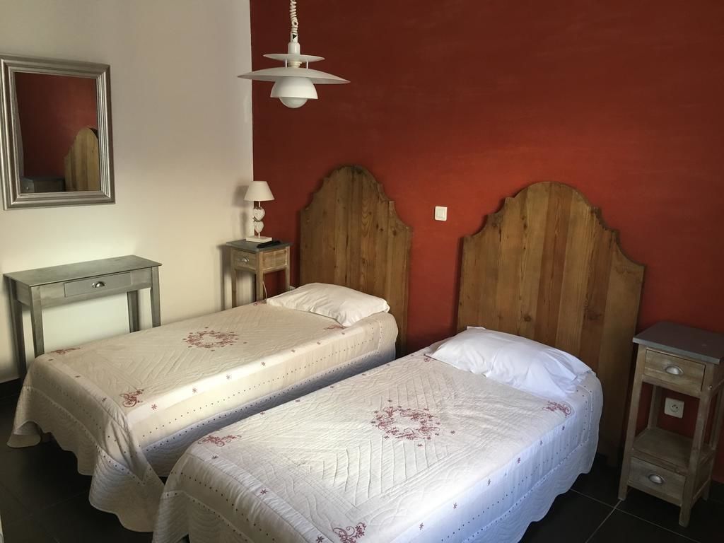 A room with two beds, a wooden headboard, a bedside table with a lamp, and a mirror on the wall.