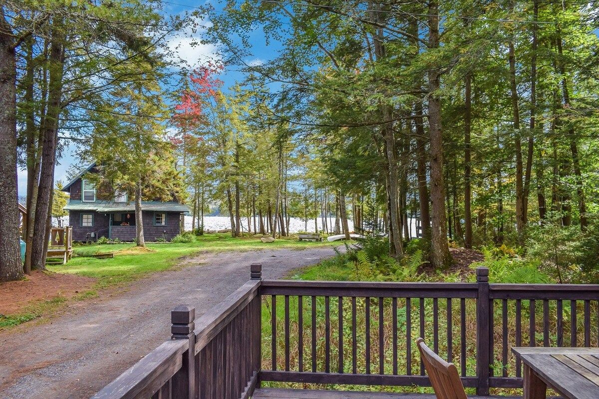 A wooden deck with a view of a cabin and forest.