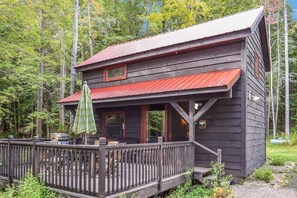A cabin with a porch, a deck, and a metal roof.