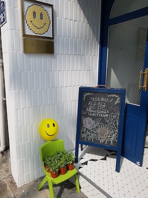 Ein Schild einer Jugendherberge mit einem Smiley und einer Kreidetafel mit Informationen für Gäste.