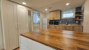 Una cocina con gabinetes de madera, un refrigerador blanco, un microondas y una cafetera.