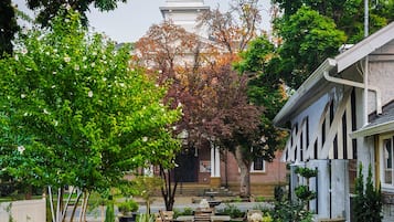 A courtyard with a flagpole, a building with a tower, and a lawn with a patterned walkway.