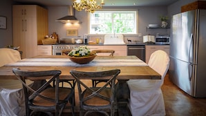 A modern kitchen with a wooden dining table, chairs, and a large bowl of flowers. - Luxury Cottage in Jacksonville's Historic Core! (Jacksonville)