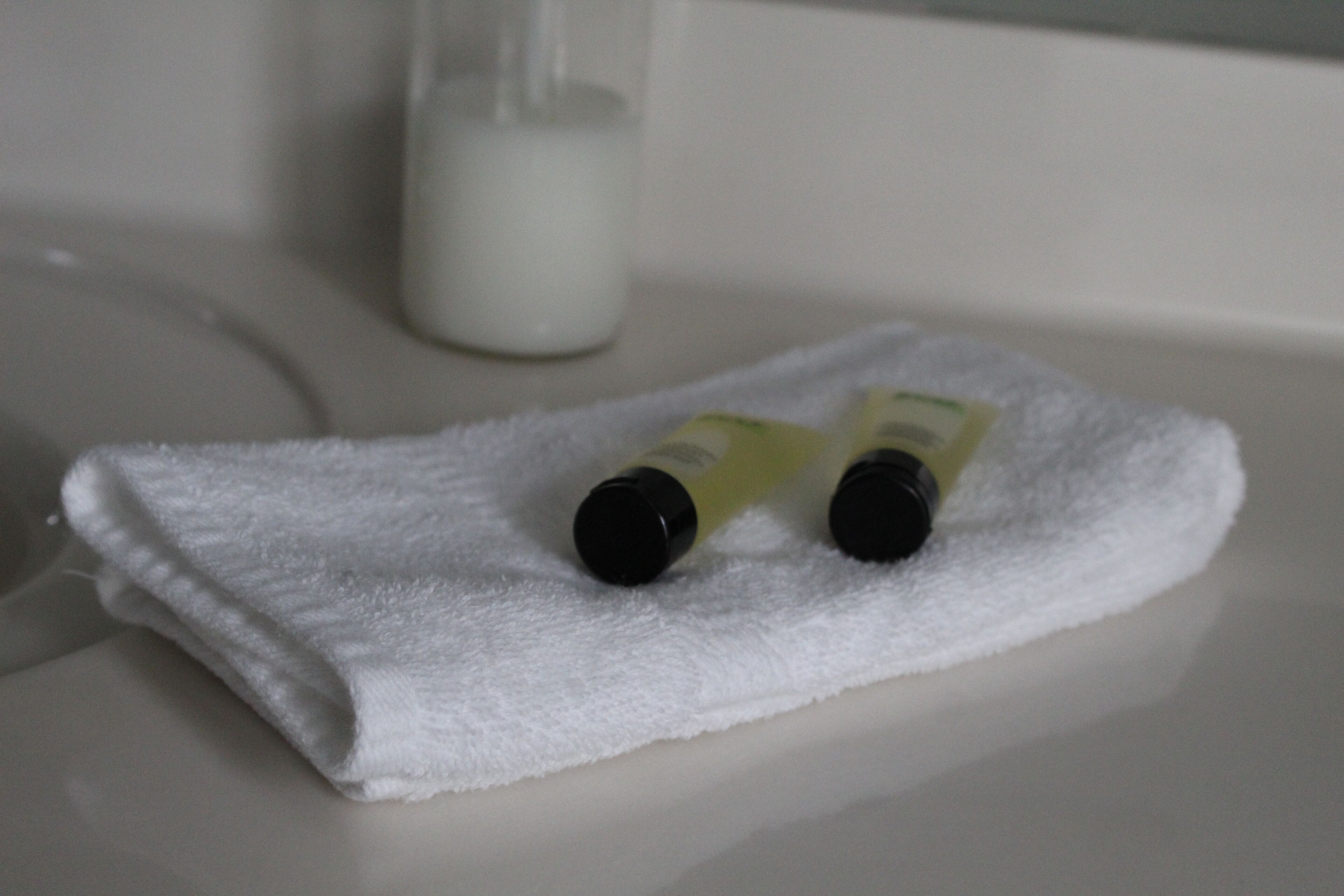 Een witte handdoek op een badkamermeubel met twee flesjes lotion.