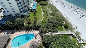 Un hôtel de grande hauteur doté d’une piscine, d’un accès à la plage et d’une végétation luxuriante.