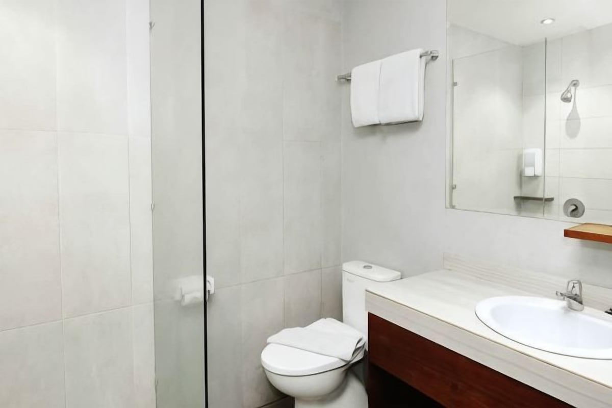 A modern bathroom with a toilet, sink, and mirror.