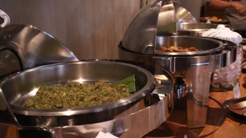 A buffet table with various food dishes in stainless steel bowls.