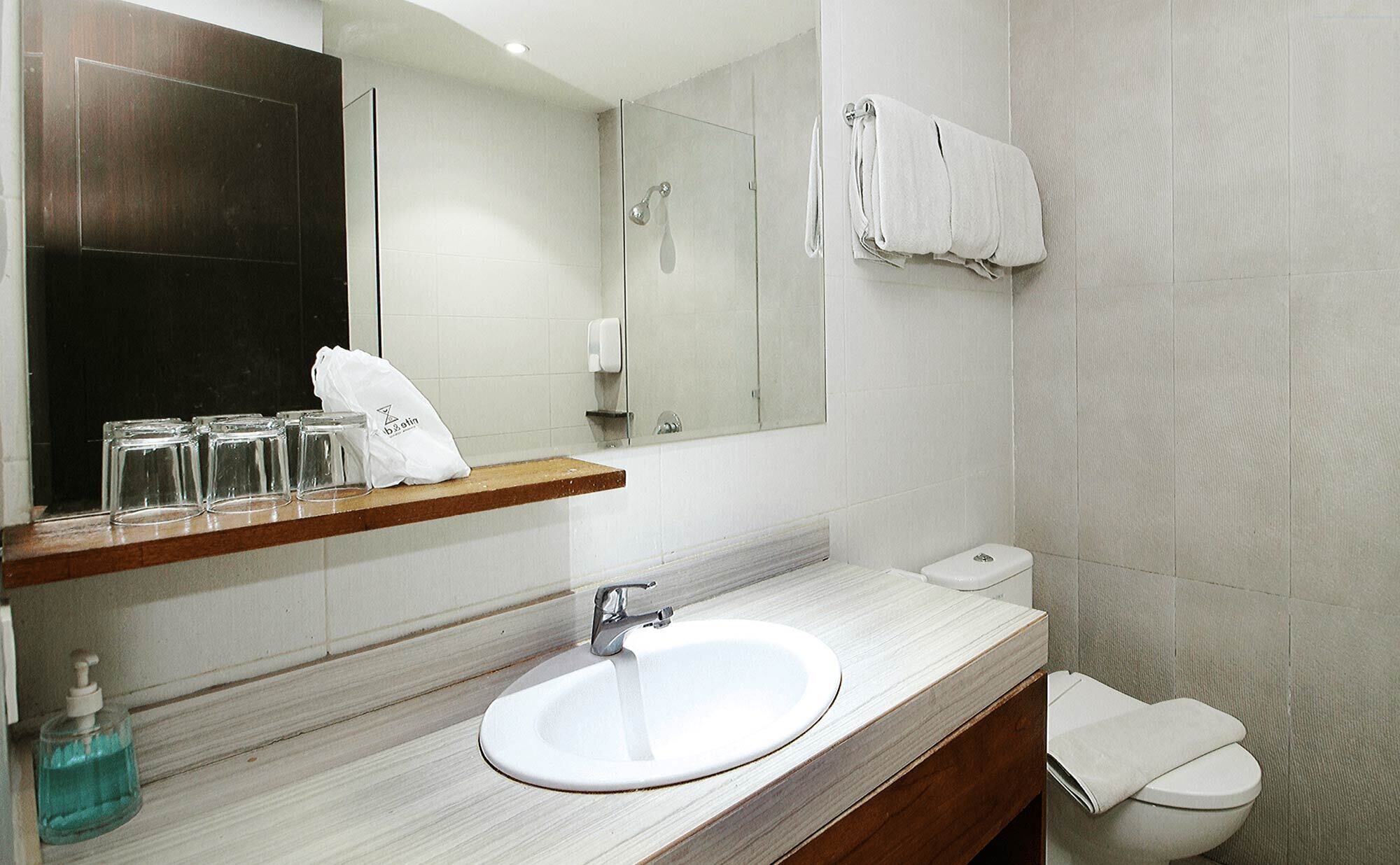A modern bathroom with a white sink, a mirror, a glass shower enclosure, and a toilet.