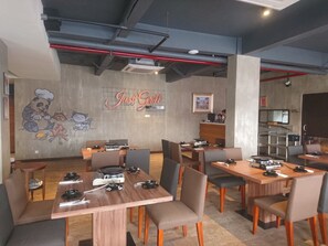 A restaurant interior with multiple tables, chairs, and a mural on the wall.
