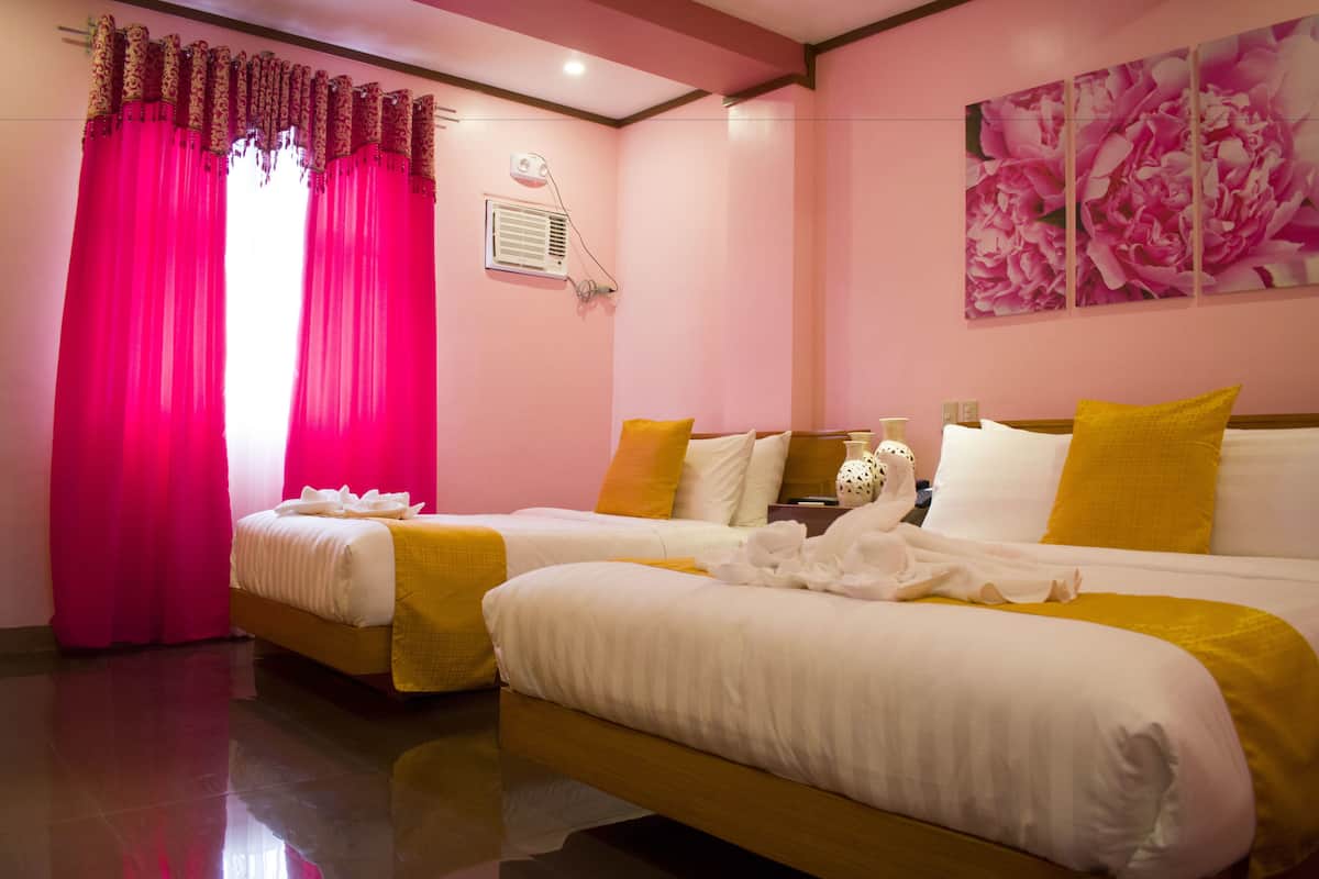 A hotel room with two beds, pink curtains, a wall-mounted air conditioner, and a floral artwork.