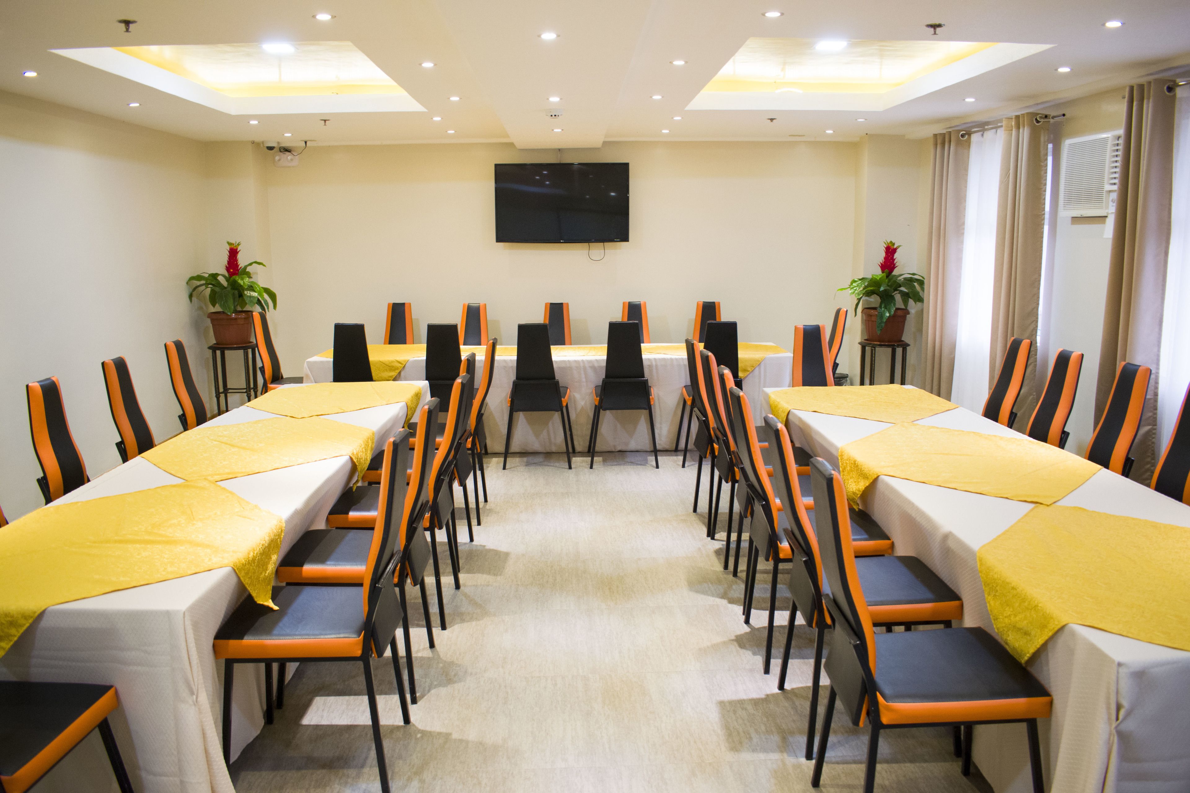 A conference room with a long table, chairs, and a TV on the wall.