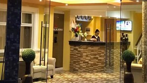 A hotel reception area with a glass entrance, a reception desk, a TV, and a sign that reads "Hotel de Royale". - Royal Mansion Hotel (Tabaco City)