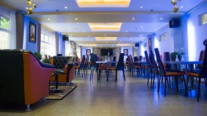 A spacious dining area with modern furniture, a fireplace, and a large window providing natural light. - Royal Mansion Hotel (Tabaco City)