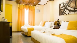 A hotel room with two beds, a wooden headboard, a yellow door, and a large abstract painting on the wall. - Royal Mansion Hotel (Tabaco City)