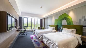 A hotel room with two beds, a desk, and a large window.