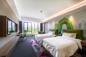 Une chambre d’hôtel avec deux lits, un bureau et une grande fenêtre.