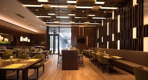 Un restaurant moderne avec un plancher en bois, des chaises recouvertes d’un tissu vert et un bar central.