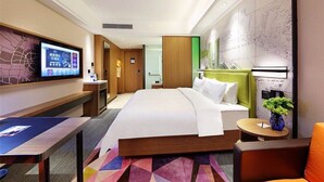 Habitación de hotel con una cama grande, un escritorio, un televisor y un mapa en la pared.
