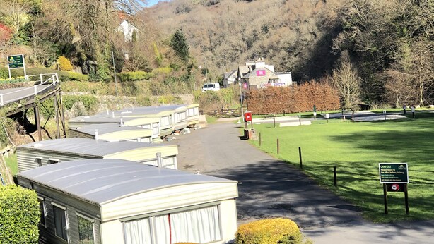 A campsite with caravans, a grassy area, and a hill in the background.