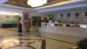 Eine Hotelhalle mit einer Rezeption, einem großen fußbodenförmigen Stern und einer Wanduhr.